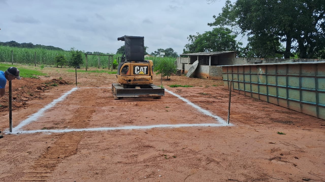 Terreno demarcado para fundação com mini escavadeira ao fundo