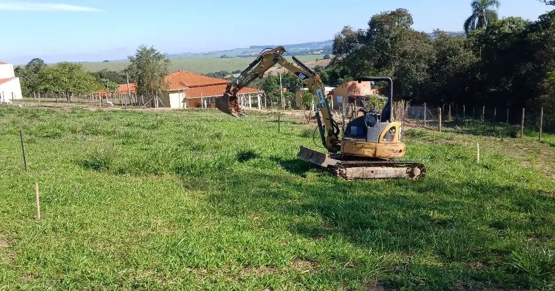 Mini escavadeira em serviço de terraplanagem em terreno amplo