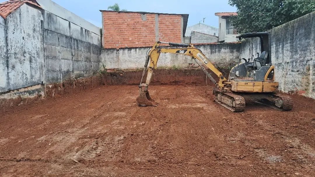 Mini escavadeira preparando solo em terreno residencial